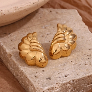 Detailed view of 18K gold plated stainless steel wave earrings on beige travertine stone