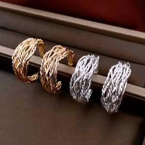 Détail de boucles d'oreilles en C plaquées or 18K et argent avec texture tissée torsadée