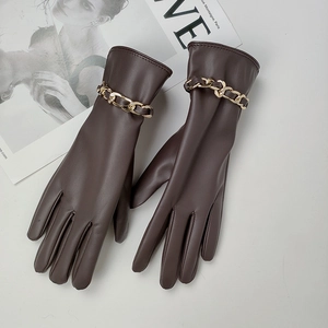 Guantes de mujer en cuero PU marrón oscuro con una gruesa cadena de metal dorado sobre blanco
