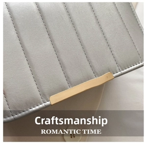 Detail of silver quilted leather bag showing golden metal clasp and vertical stitching