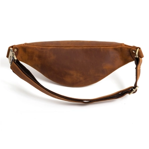 Vue détaillée du cuir vintage marron et de la boucle en bronze de la sacoche banane