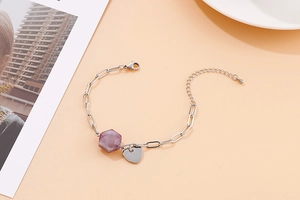 Detail of silver paperclip chain bracelet with purple hexagonal bead and heart charm