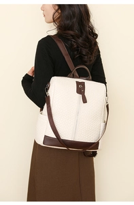 Detailed side view of cream quilted backpack with brown leather trim worn by model