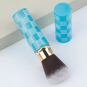 Detail of retractable makeup brush with blue checkered handle and soft dual-tone bristles