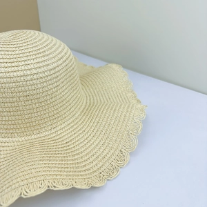 Detailed view of woven straw sun hat texture and wide brim wavy edge craftsmanship