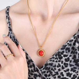 Luxury gold necklace set with red stone pendant and textured ring on female model