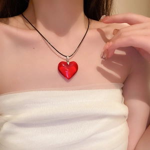 Gros plan d'un pendentif coeur en résine rouge sur un collier noir porté par un mannequin