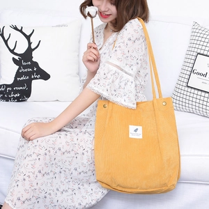 Bright yellow corduroy tote bag with dual shoulder straps shown in a bright lifestyle setting