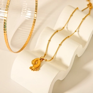 Detailed view of 18K gold plated stainless steel necklace with foot pendant on display