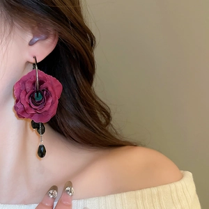 Close-up of elegant dark red fabric rose earrings with black beaded fringe tassels