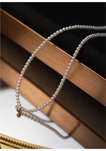 Macro shot of minimalist freshwater baby pearl choker with 14K gold bean detail