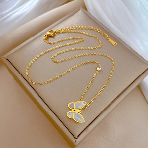 Close-up of golden butterfly necklace with white mother of pearl inlay and round zircon
