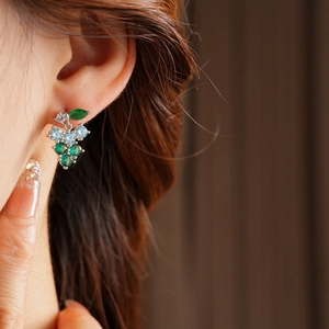 Macro close-up of grape-shaped tassel earrings with green and blue zircon stones on model