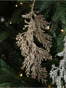 Golden and silver cypress leaf ornament with glitter detail on a Christmas tree