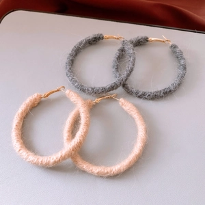 Detailed close-up of dark grey and light pink woolen yarn wrapped hoop earrings