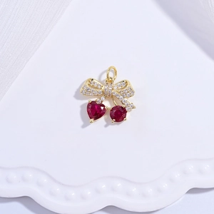 Macro shot of gold cherry pendant with red heart crystals on a white wavy tray