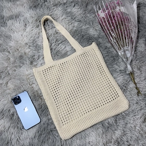 Close-up of beige crochet knit tote bag showing dense woven cotton texture on plush rug