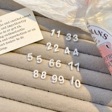 Macro view of white resin number nail charms from 11 to 99 on a gray velvet display