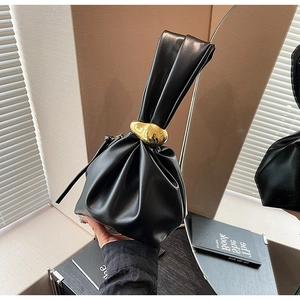 Detail view of black pleated bucket bag with gold irregular metal buckle and leather handle