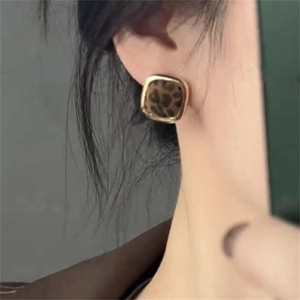 Close-up of a model wearing square leopard print earrings with a gold metal frame