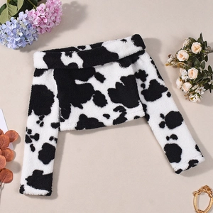 Detail shot of black and white cow print plush off-shoulder top on beige background