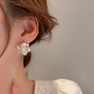 Elegant white flower earrings with pearl center and gold trim shown on model