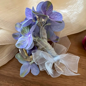 Detailaufnahme der lila Organza-Blumen-Haarklammer mit Schleife auf Holztisch