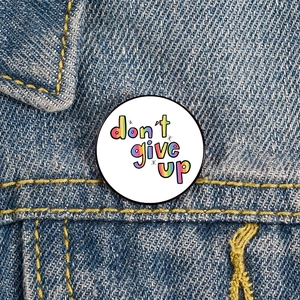 Mental Health enamel pin with 'Don't Give Up' quote on dark blue denim jacket