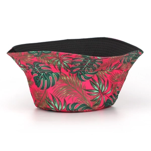 Detailed view of pink sun hat with green tropical leaf prints and black inner lining