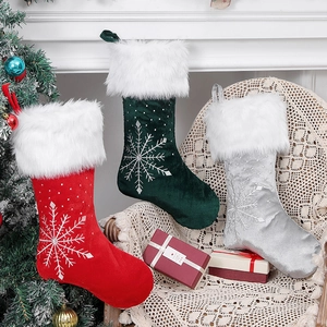 Three velvet Christmas stockings in red green and grey with embroidered snowflake patterns