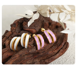Detailed close-up of C-shaped layered enamel earrings in white and lavender with gold edges