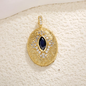 Macro shot of gold-plated oval pendant featuring a dark blue gemstone and small diamonds