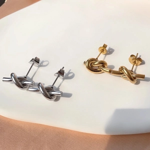 Polished knot stud earrings in gold and silver finishes on elegant white display