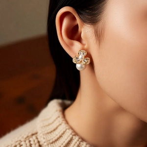 Close-up of elegant flower pearl earrings with sparkling zircons worn by a model