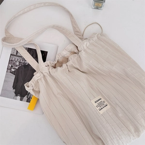 Macro detail of creamy pleated tote bag with drawstring closure and brand label