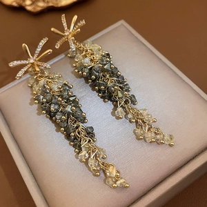 Detailed close-up of long tassel earrings with grey crystals and gold-tone finish