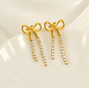 Detail view of gold bow earrings with crystal tassels on a decorative ceramic shell dish