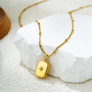 Détail d'un pendentif soleil plaqué or 18K avec zircon sur une pierre blanche