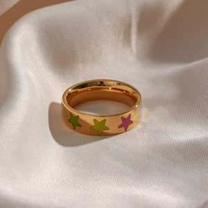 Macro shot of 18K gold plated ring with colorful star patterns on white silk