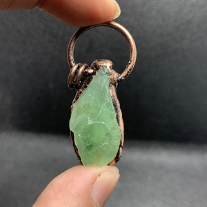Dettaglio di pendente in fluorite verde con filo di bronzo vintage e grande gancio