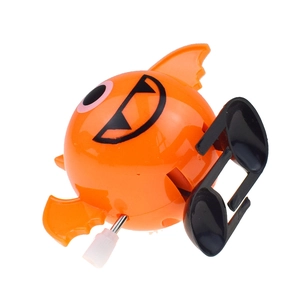 Macro detail of wind-up orange bat toy showing metal mechanical rod and white plastic knob