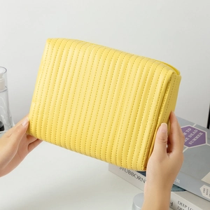 Detailed view of yellow quilted cosmetic bag with metal zipper and luxury textured finish
