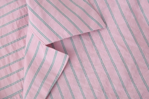 Gros plan sur les coutures du col et le tissu en coton à rayures roses de cet ensemble