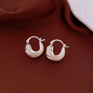 Close-up of vintage silver earrings with cream enamel finish on dark silk background