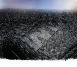 Gros plan du logo DWV embossé sur une casquette en cuir noir avec texture grainée