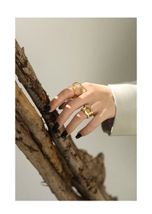 Macro shot of minimalist gold rings with hollow chain and multi-layer band design