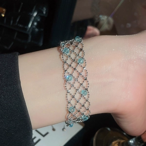 Detail of light blue crystal beaded bracelet with silver metal mesh design on a woman's wrist