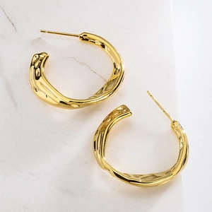 Minimalist gold-plated C-shaped earrings with hollow irregular wave design on marble