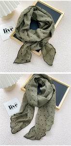 Detailed macro shot of olive green polka dot linen scarf with frayed edges texture