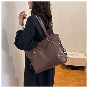 Detail view of deep brown large tote bag showing smooth faux leather and gold metal hardware